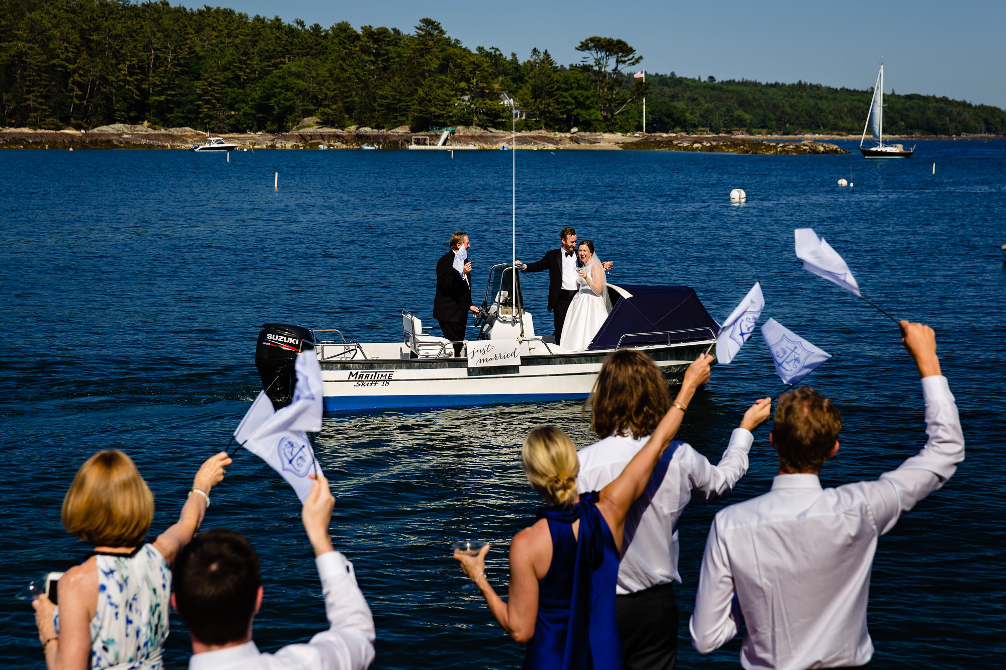 The couple exit the wedding via boat at their Blue Hill Maine ceremony and reception