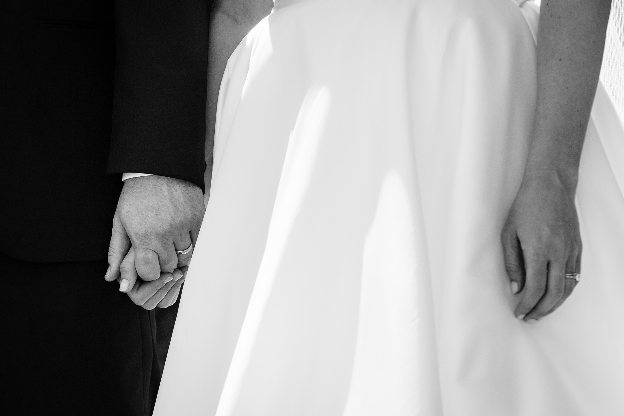 A bride and groom hold hands tenderly during a wedding ceremony in Maine
