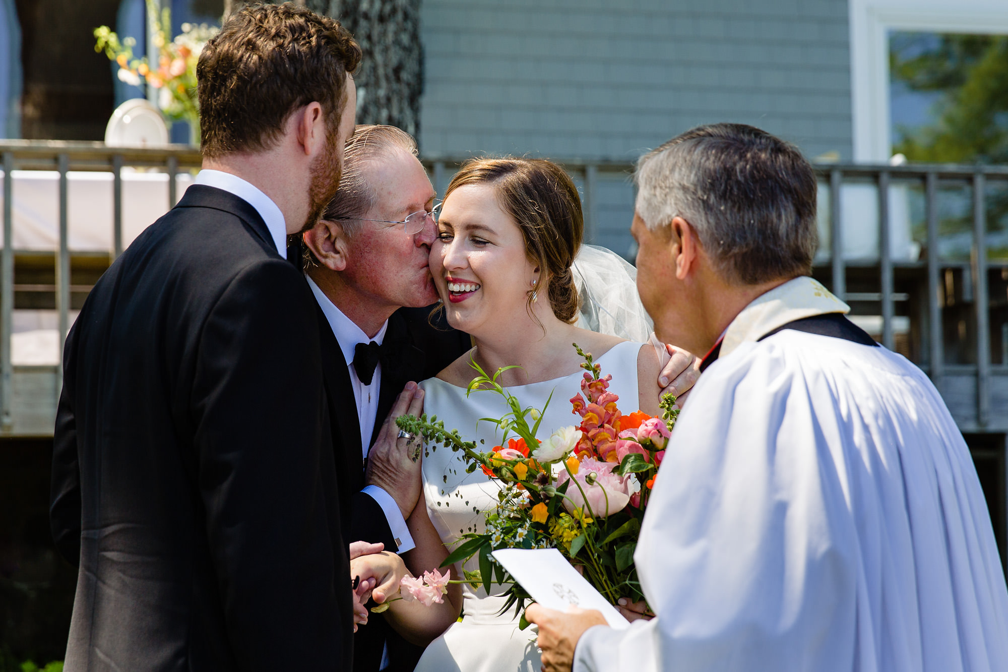 The father of the bride kisses the bride at an intimate Blue Hill Maine wedding
