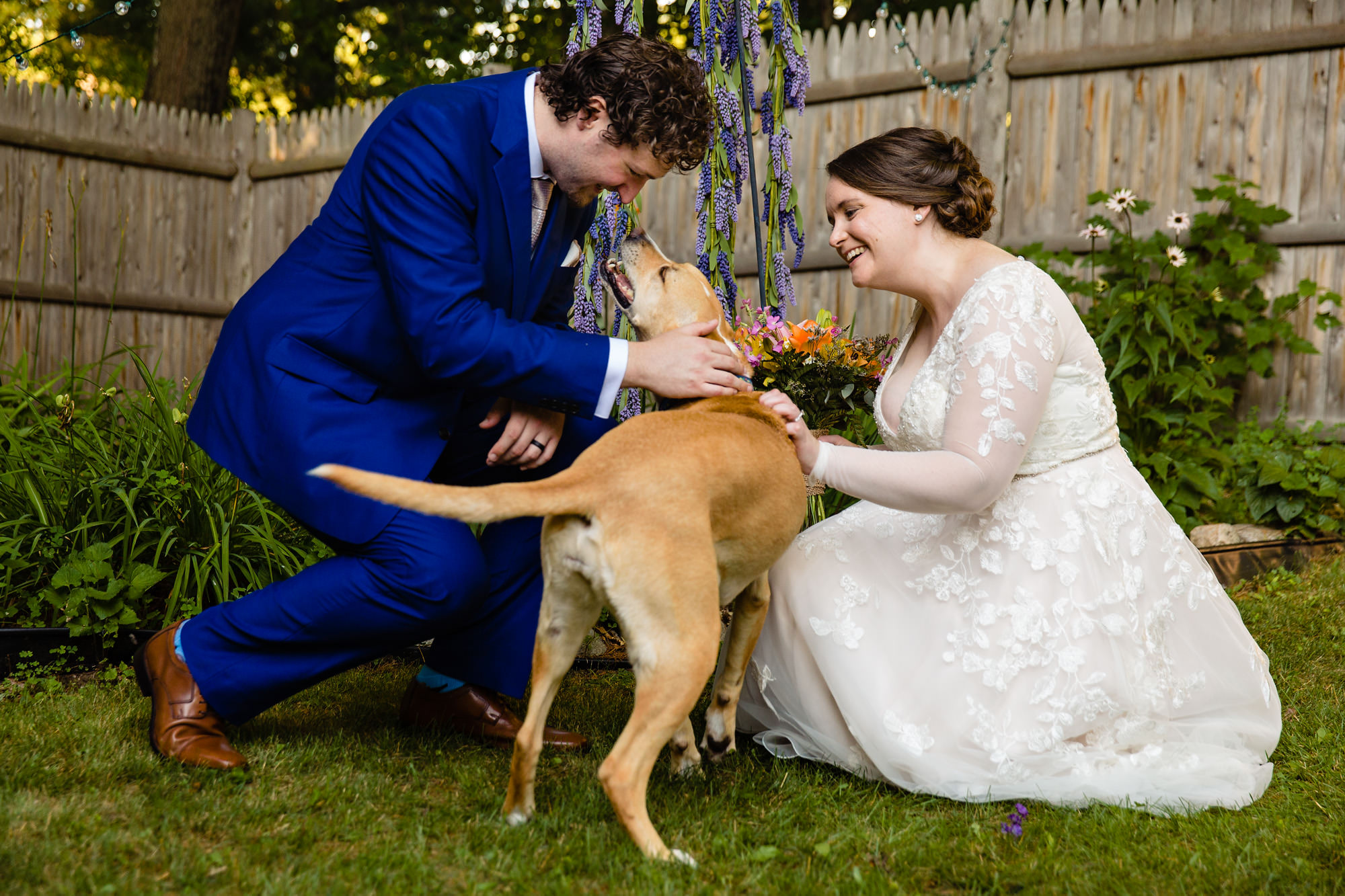 A couple loves on their dog after their wedding ceremony