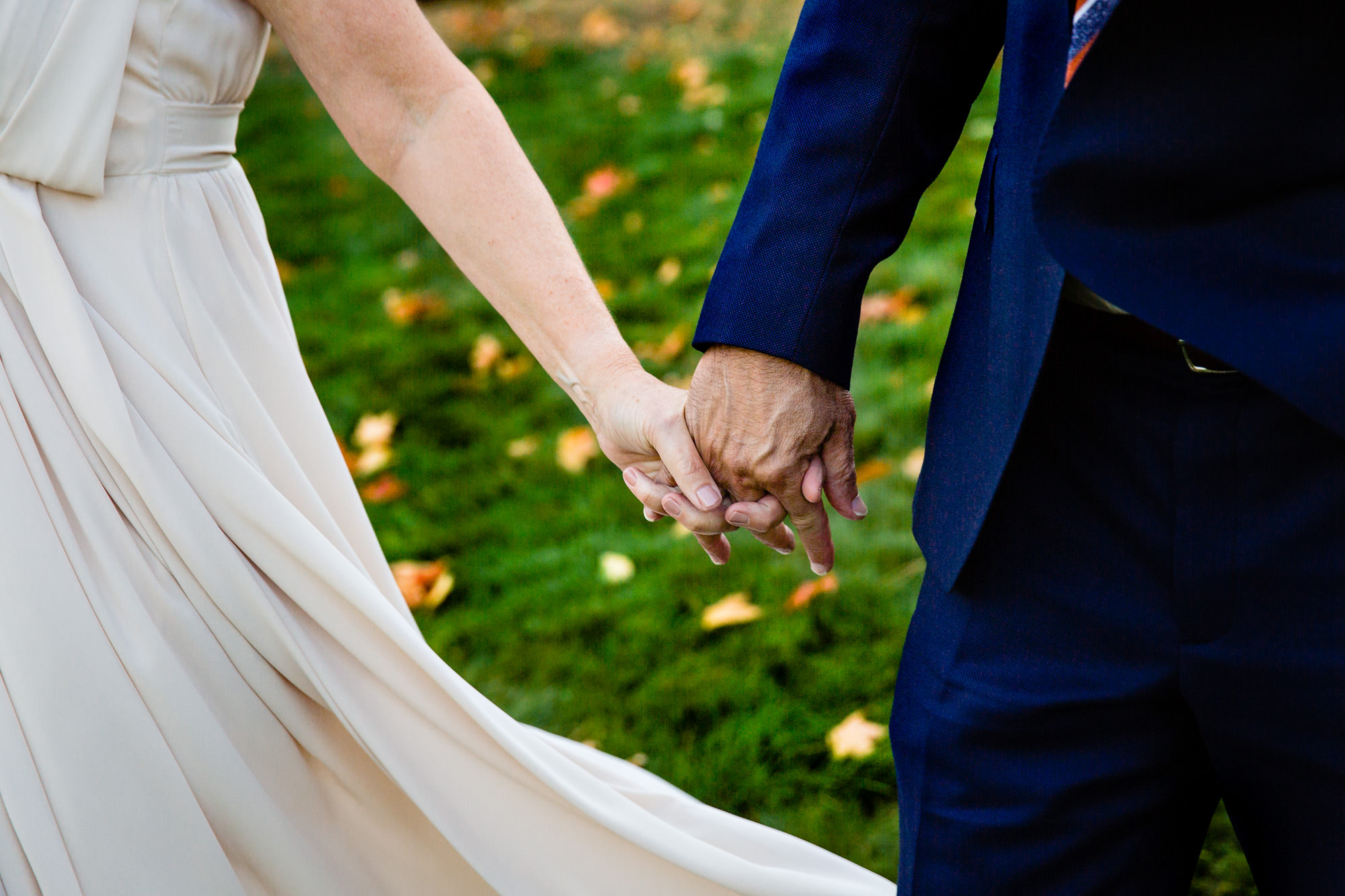 A couple holds hands at a wedding in Maine