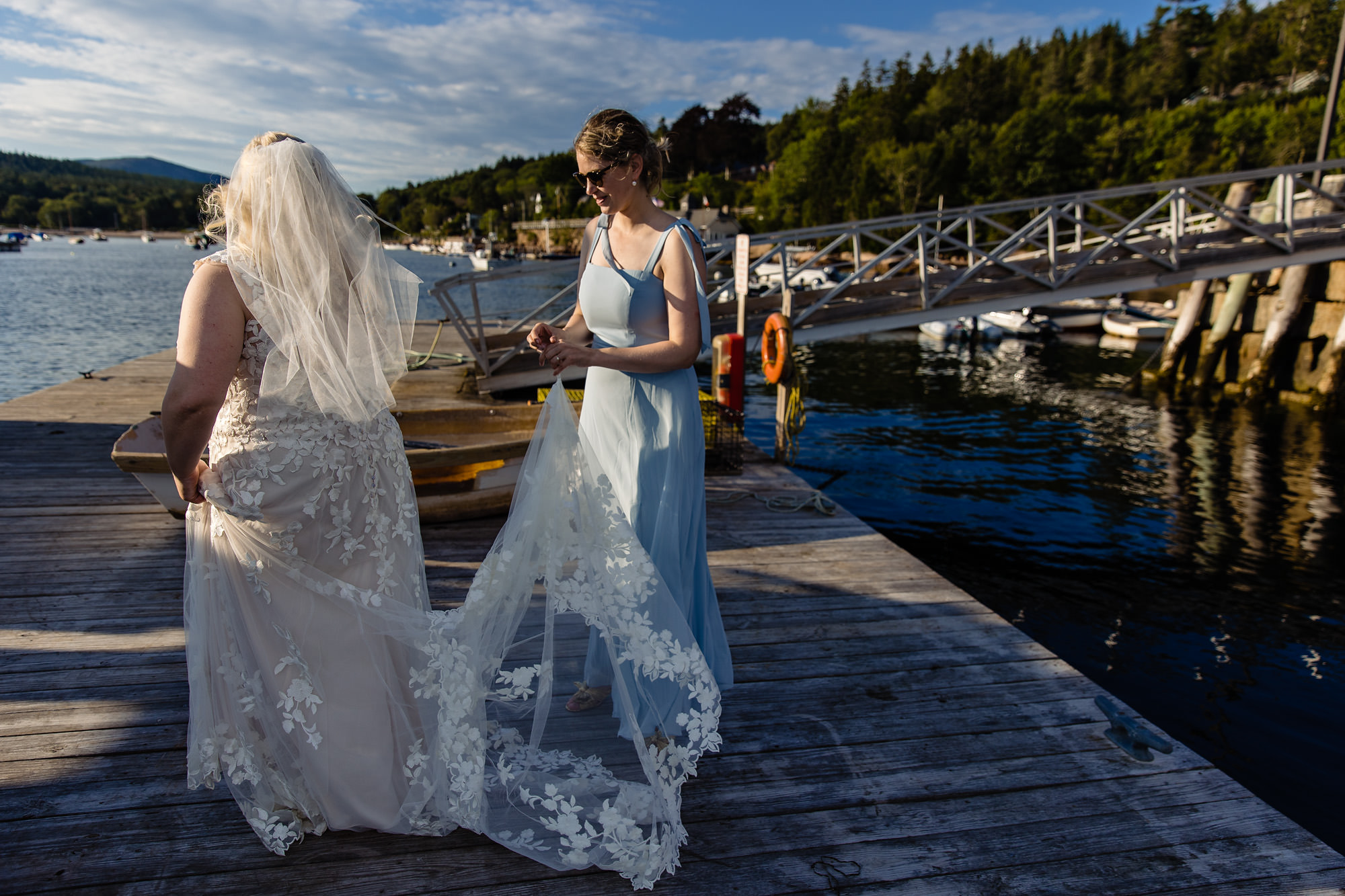 The Maid of Honor helps Martha bustle her dress at her intimate wedding in Northeast Harbor
