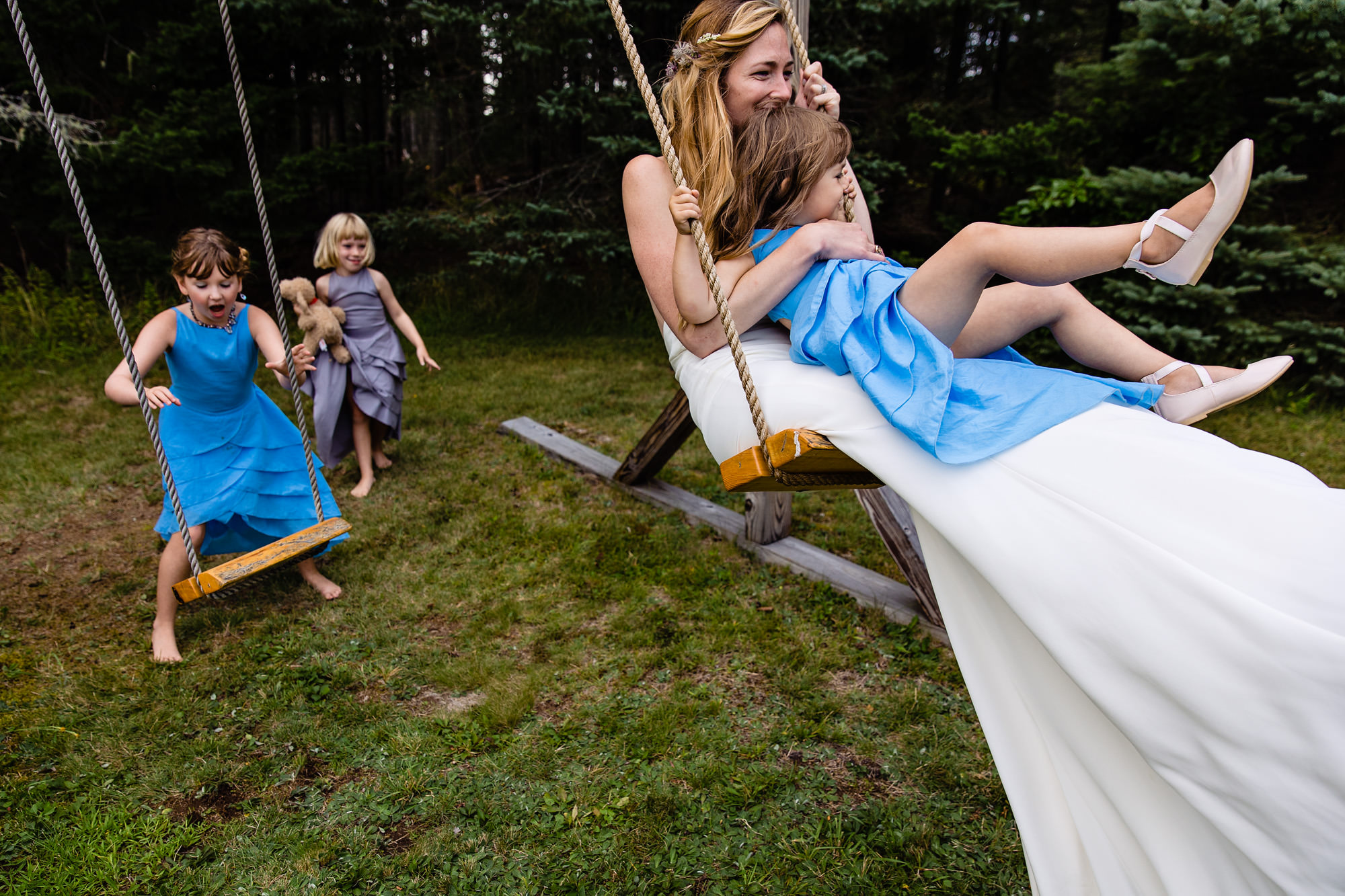 A wedding couple are pushed by flower girls on the swings at their wedding in Maine