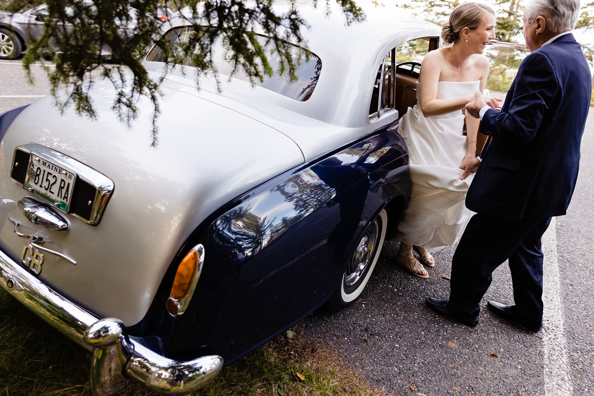 A bride gets out of a vintage car for her Acadia wedding ceremony