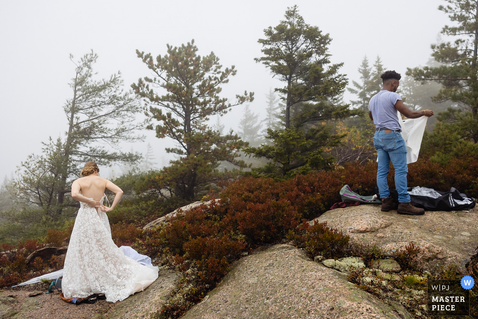 A bride and groom get dressed on top of a foggy mountain in Acadia