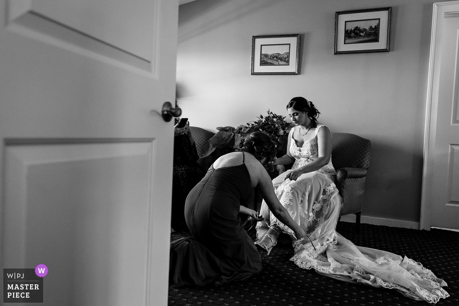 A bridesmaid helps the bride with her shoes at a Bar Harbor wedding