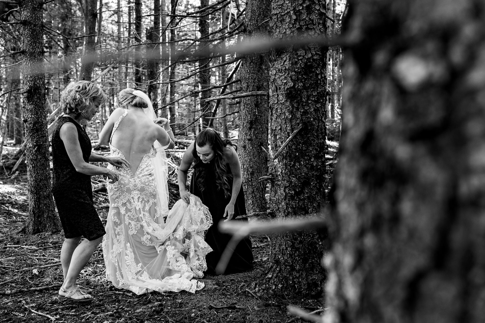 A bride gets dressed in the middle of the woods in Maine