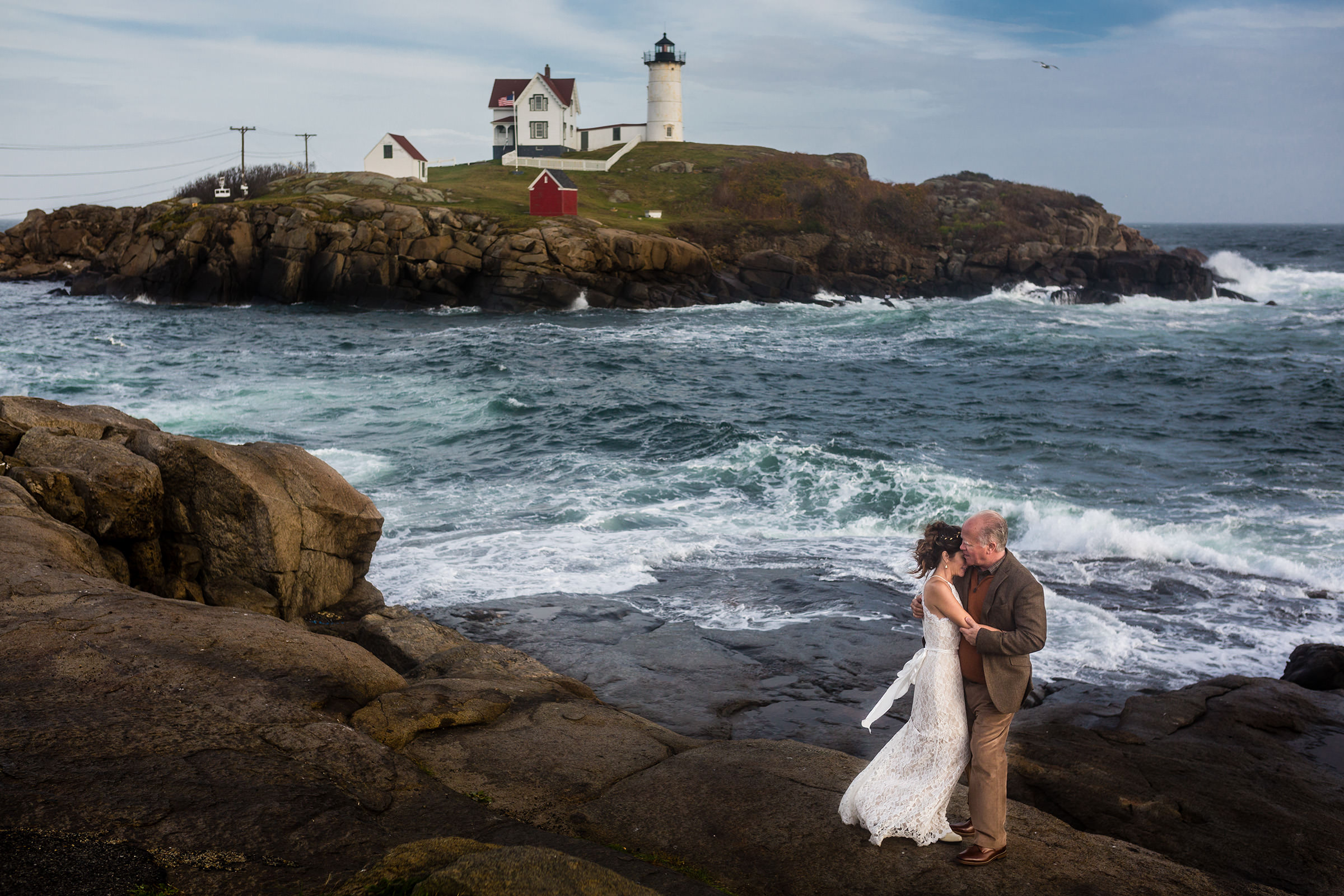 A couple hold each other during their elopementin front of Nubble Lighthouse