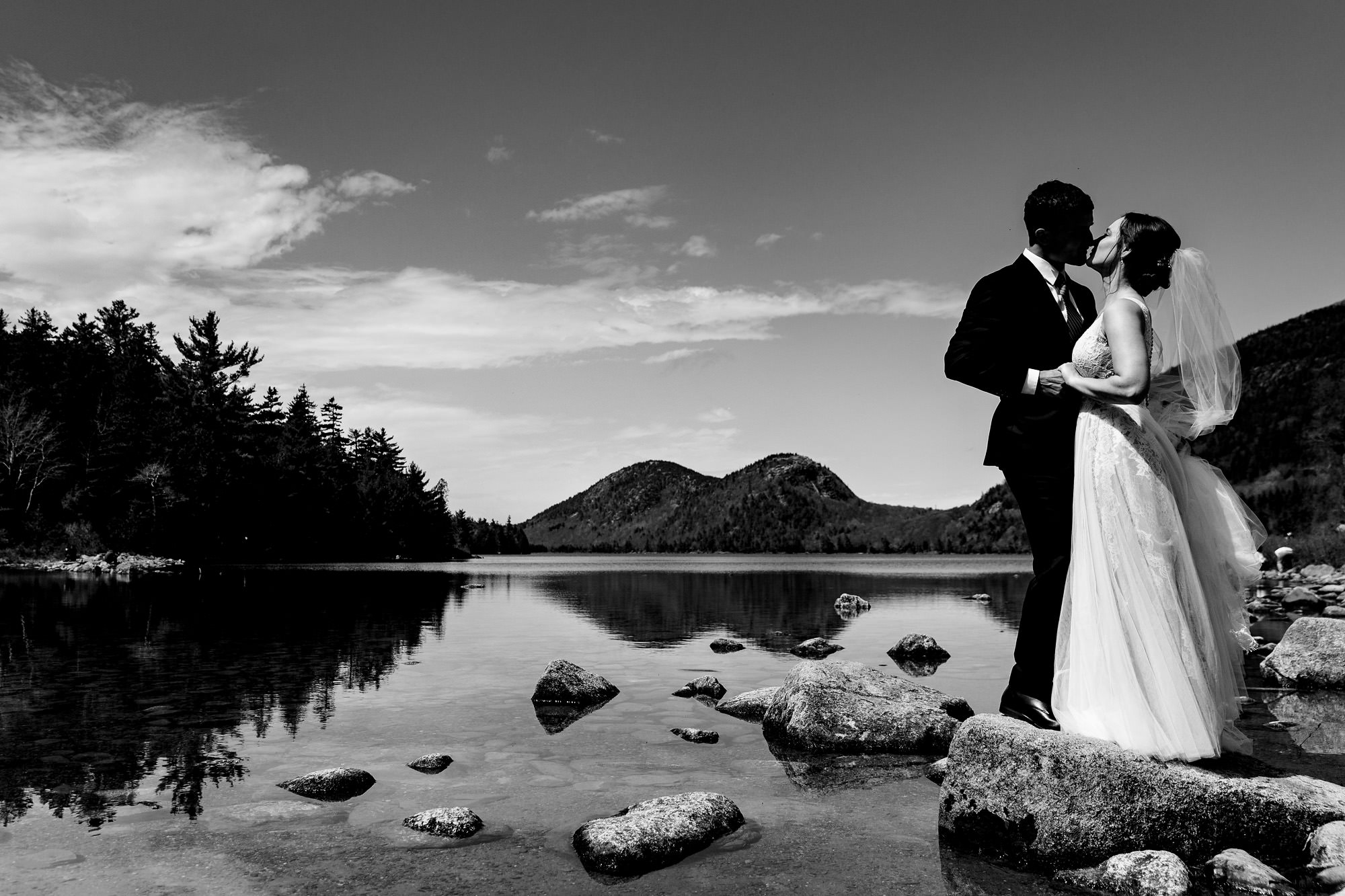 A wedding couple poses in front of Jordan Pond in Acadia