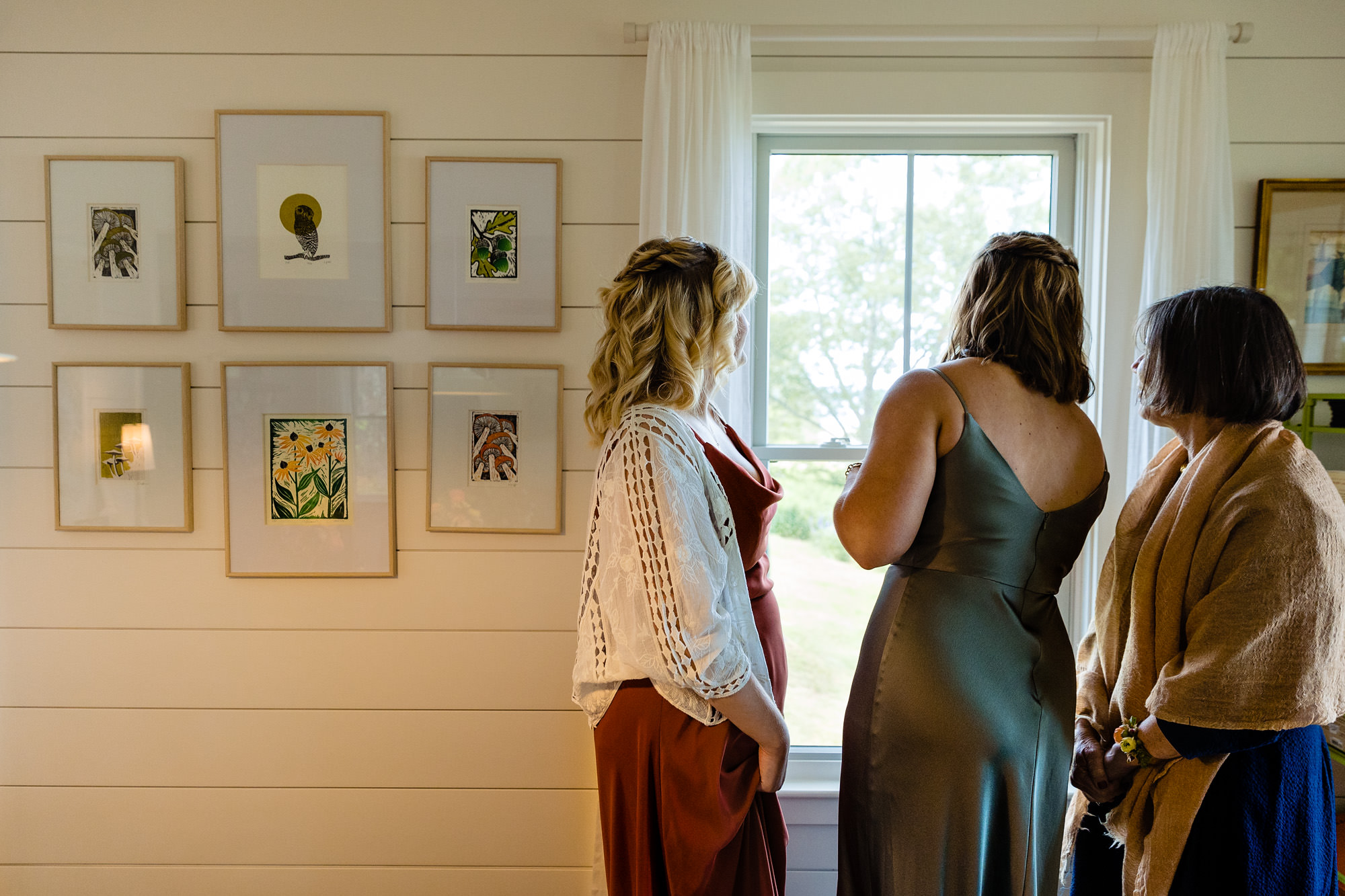 Bridesmaids peek out the window at guests arriving for the wedding ceremony at Chebeague Island