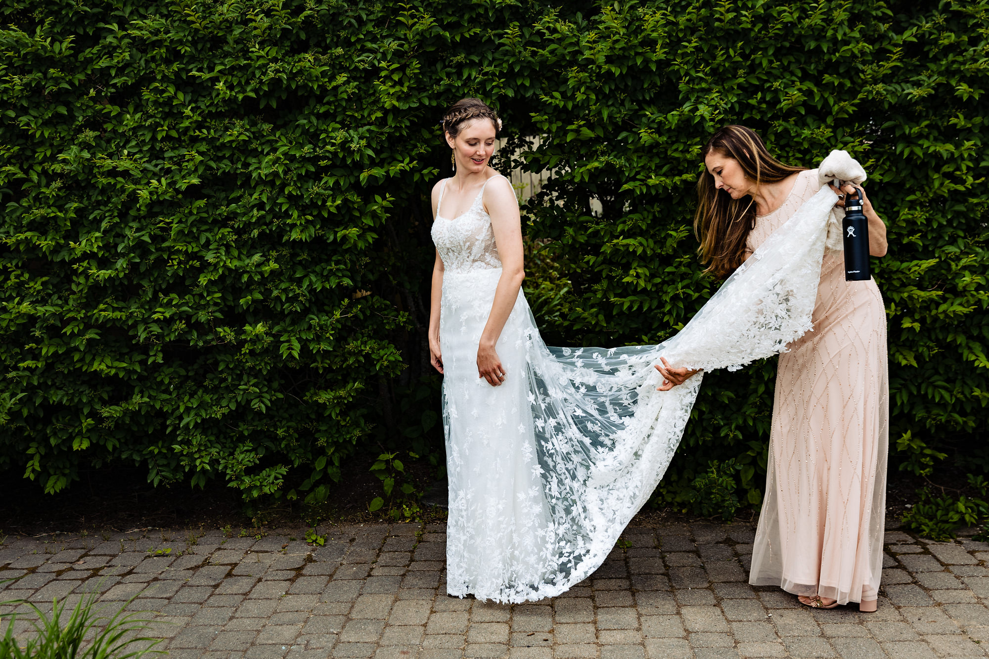 The mother of the bride helps the bride with her wedding dress