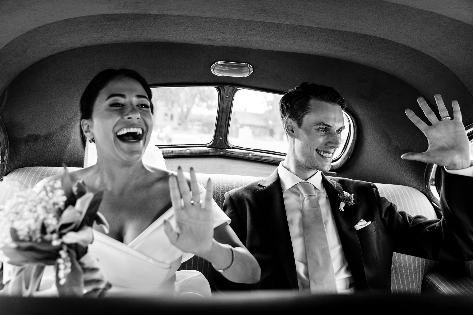 The wedding couple waves as they leave their wedding ceremony
