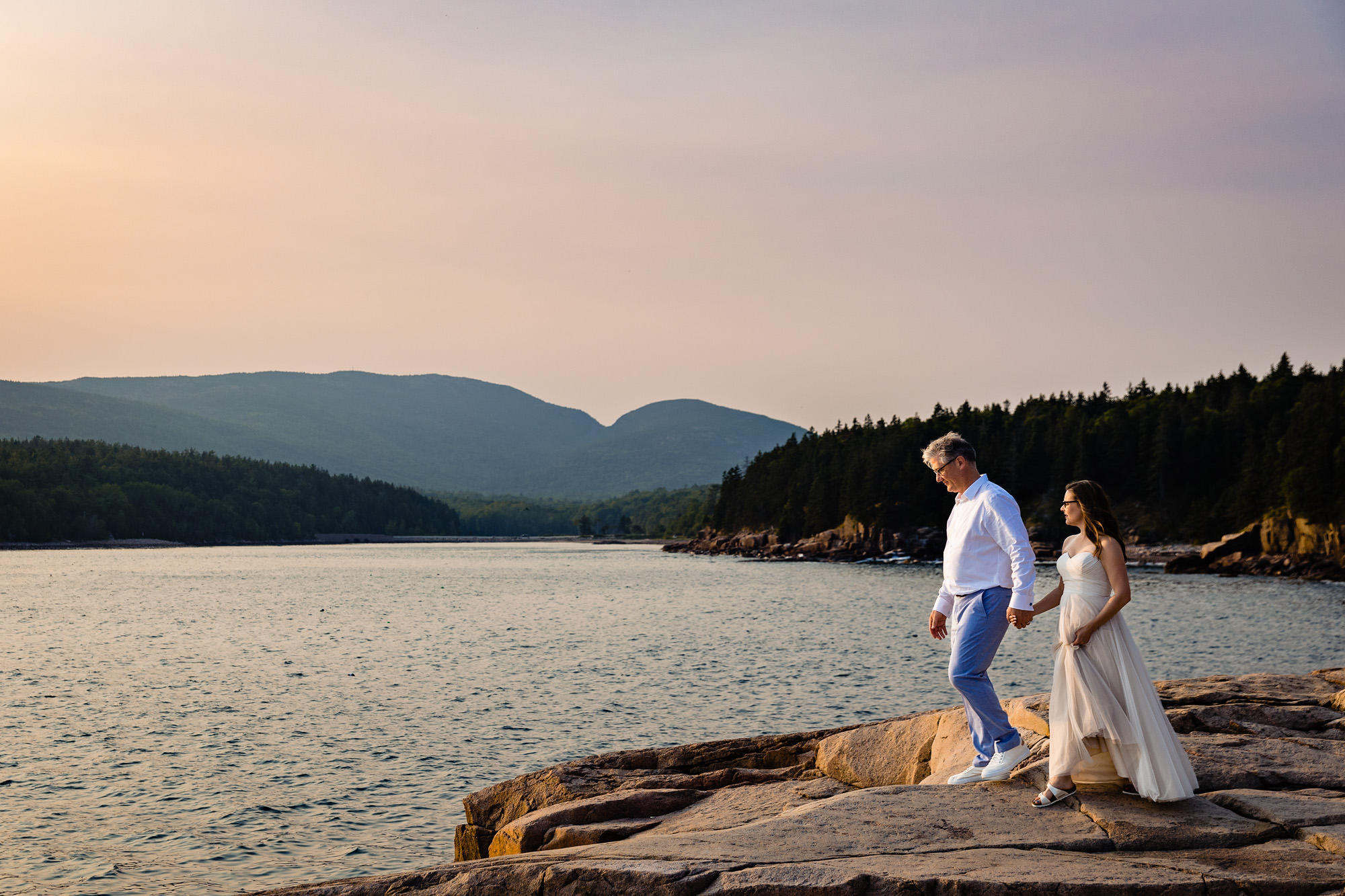 A bride and groom walk on the cliffs of Acadia National Park for portraits at their elopement