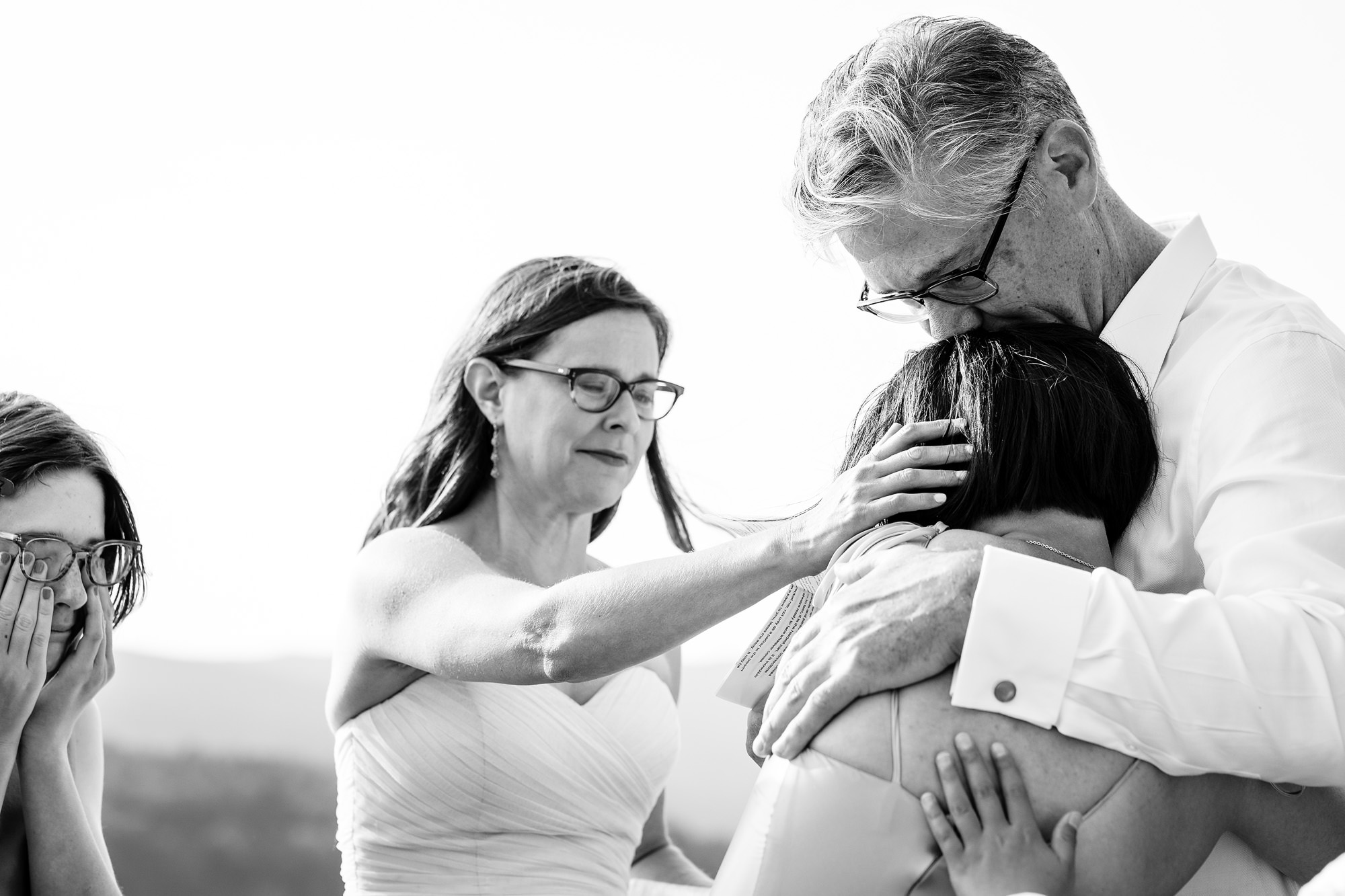 The bride and groom embrace the groom's daughter, while the bride's daughter cries.