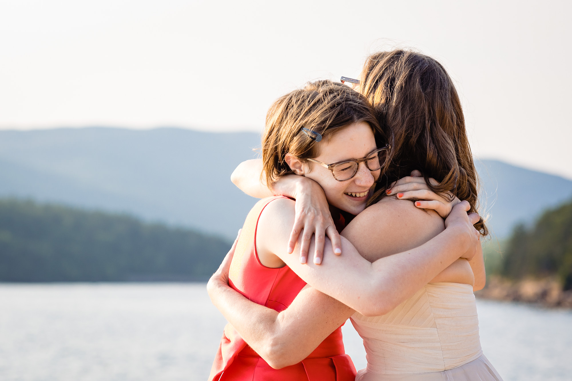 A bride and her daughter embrace on the cliffs of Acadia