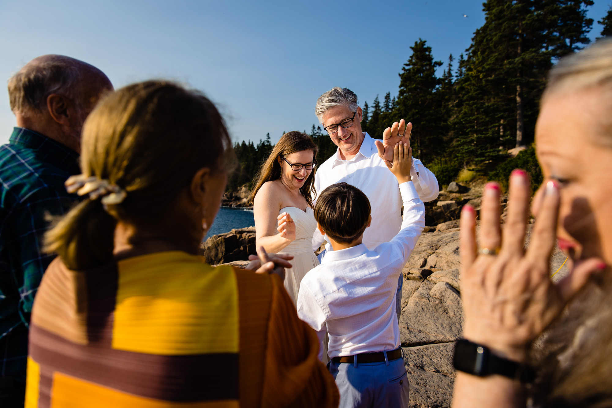 The bride and groom give a high five to the groom's son while another family member cries