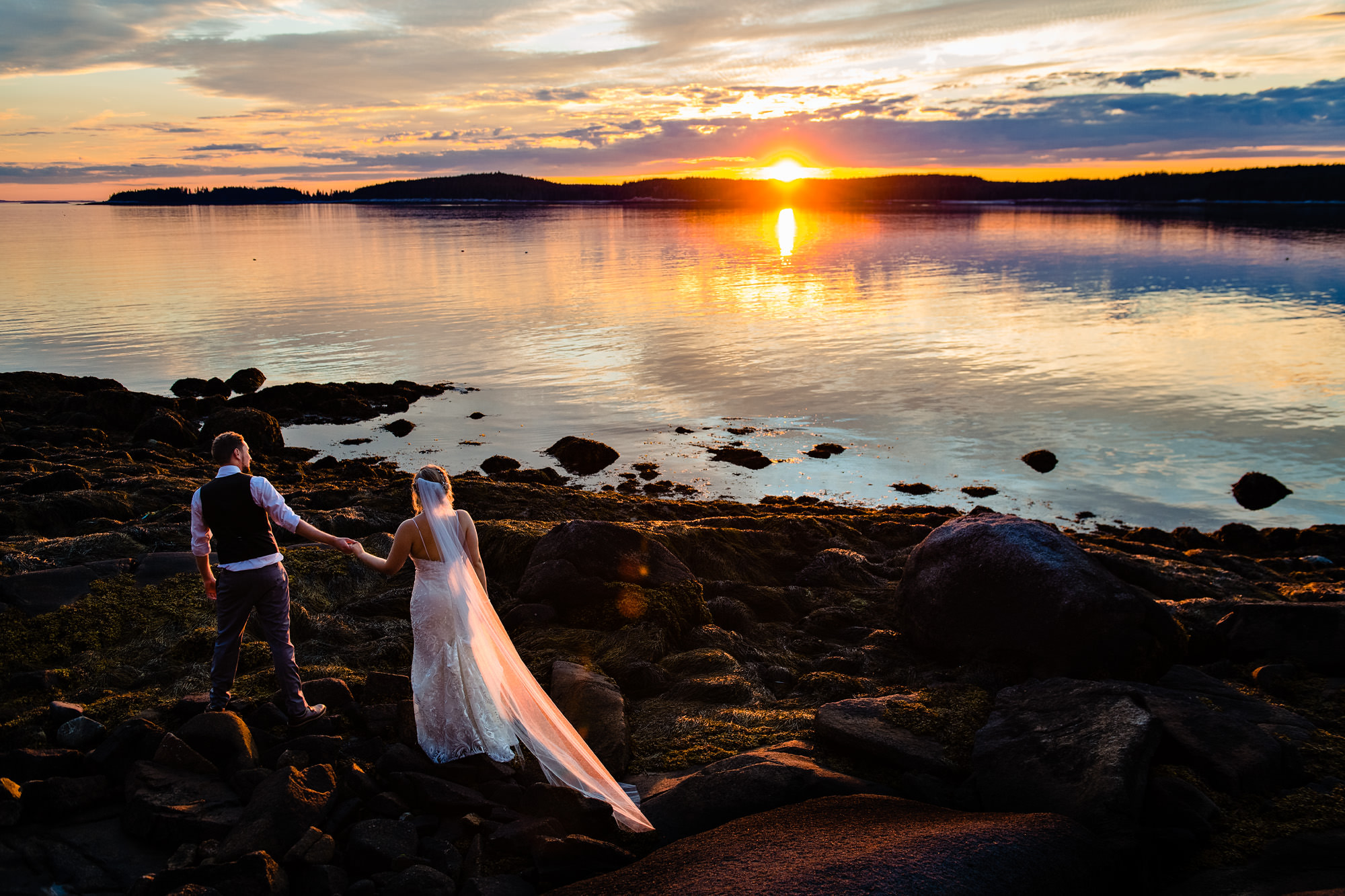 A wedding couple watch the sunset on Swans Island, Maine