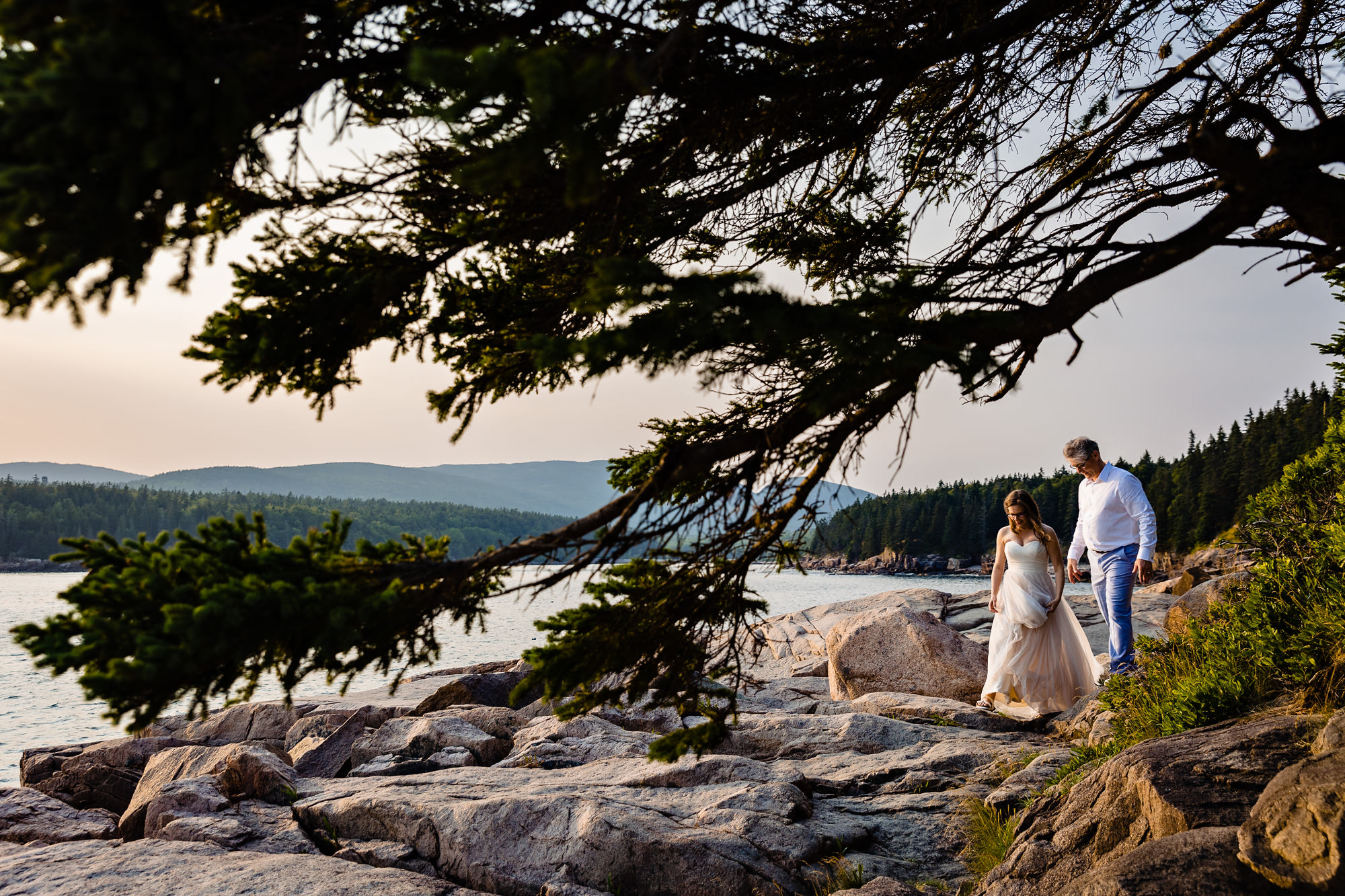 A bride and groom walk on the cliffs of Acadia National Park for portraits at their elopement