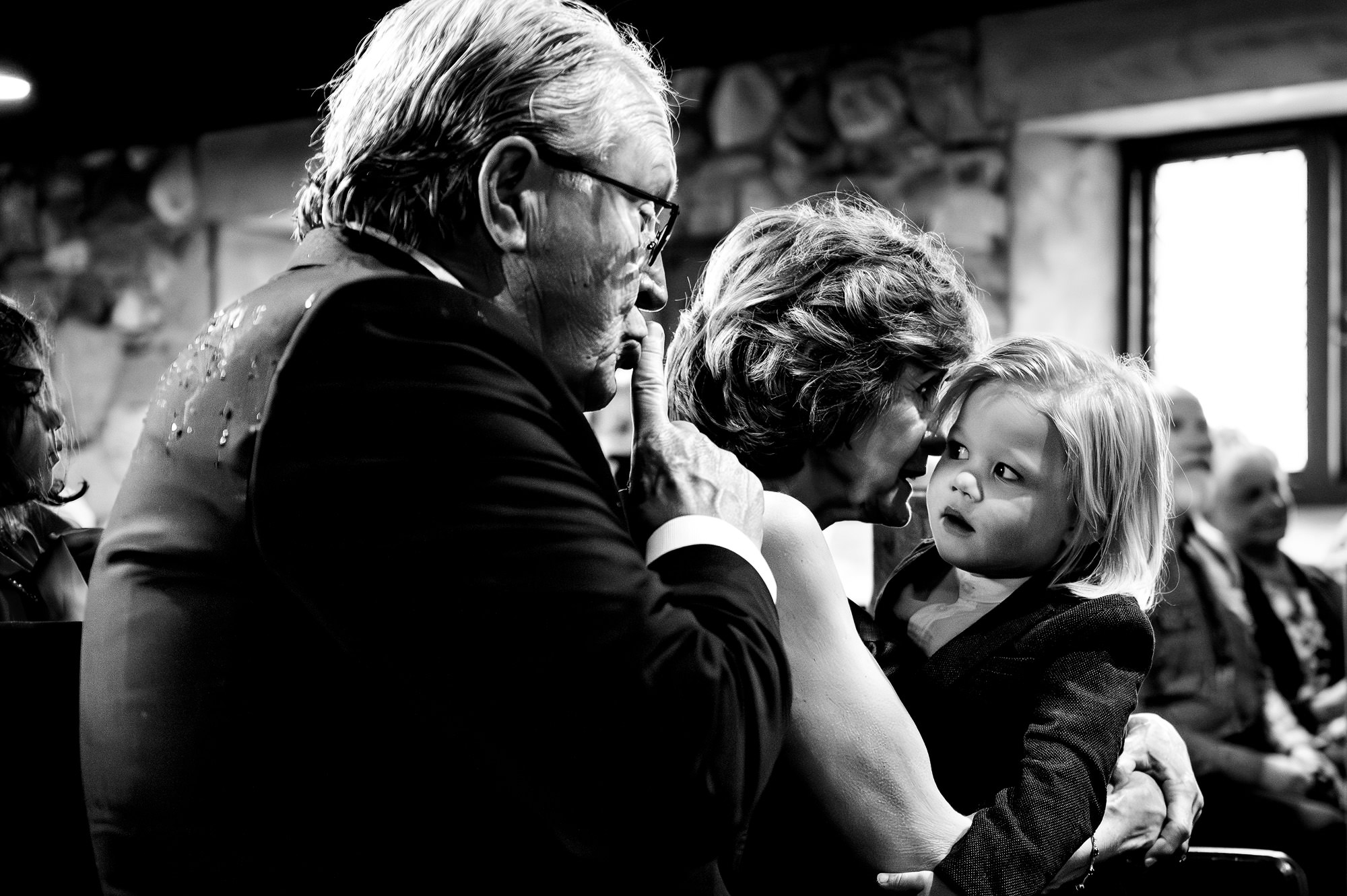 A man shushes a loud child during a Maine wedding ceremony.