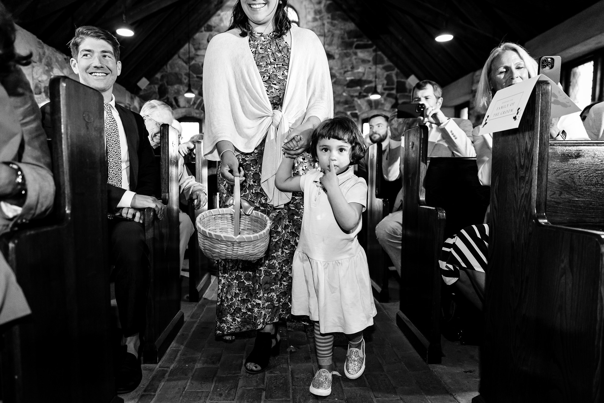 The flower girl picks her nose while participating in a wedding ceremony.