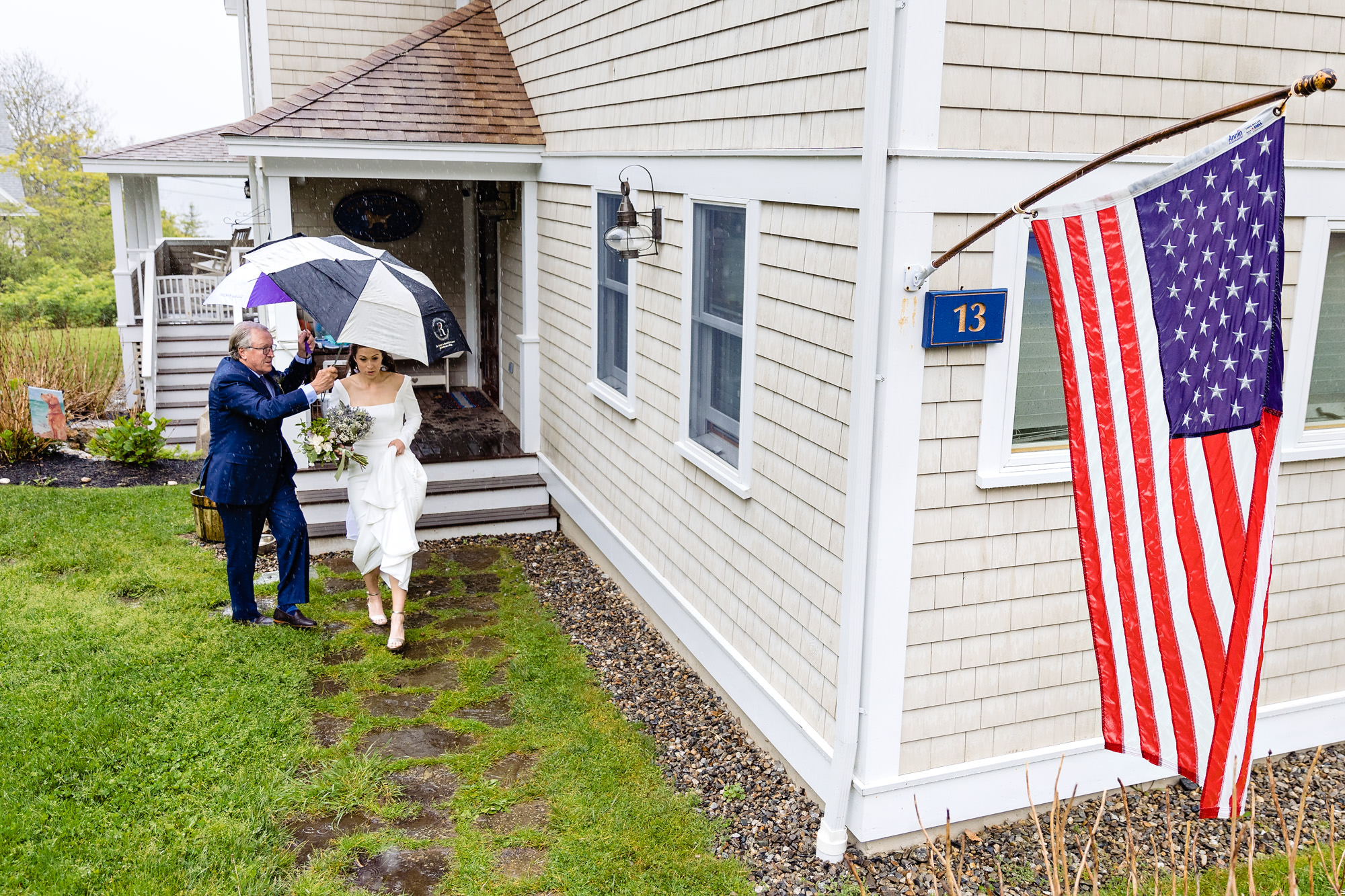 The bride is shielded by her dad as she walks in the rain to her Boothbay Harbor wedding.