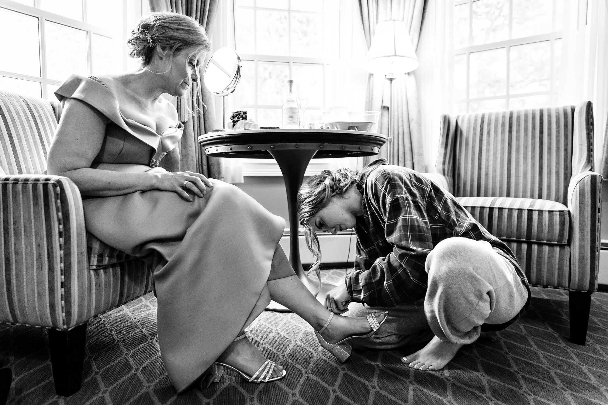 A bride helps her mom put her shoes on at her wedding at the Bar Harbor Inn in Maine.