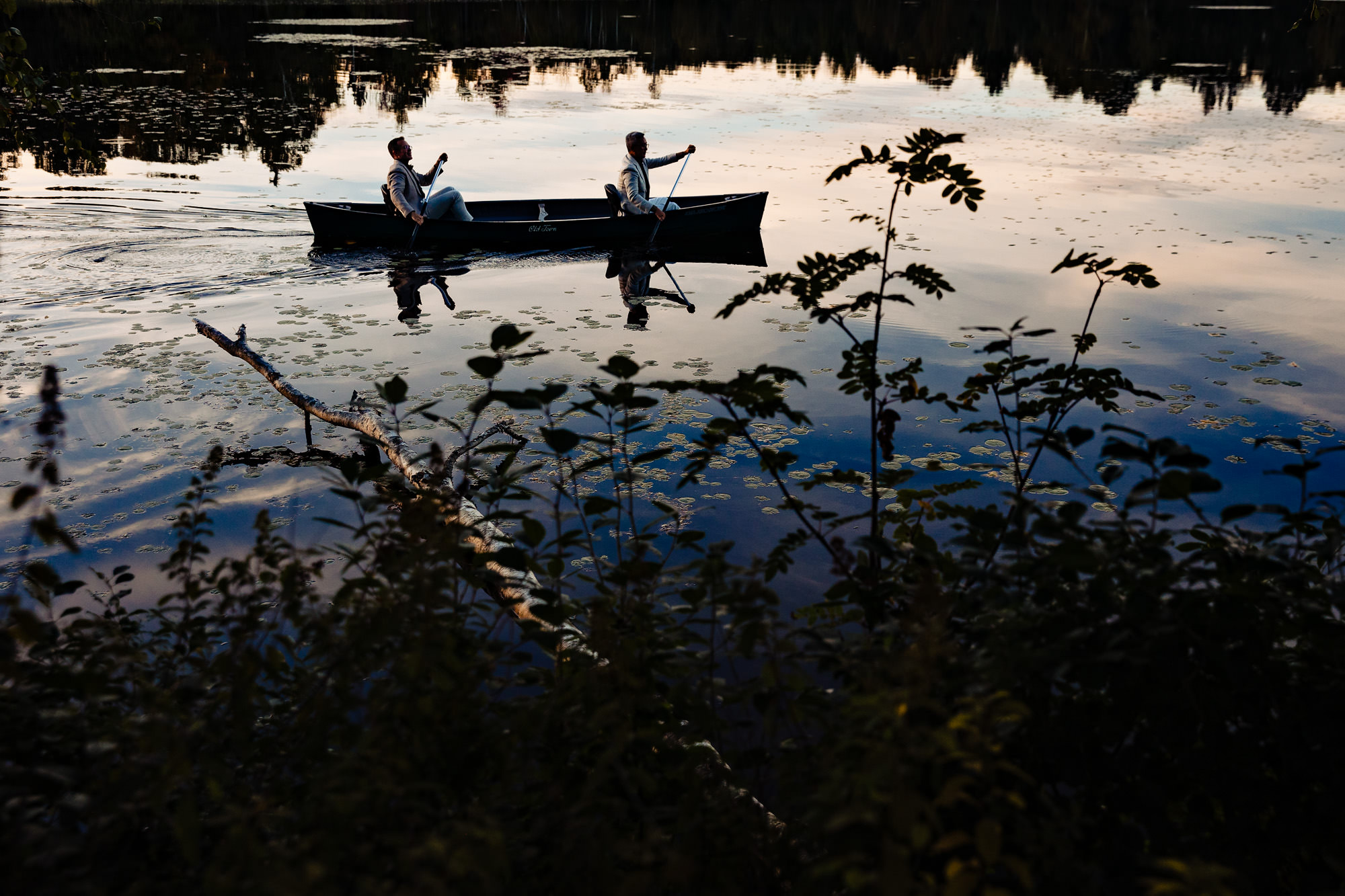 The grooms jumped into a canoe for sunset portraits at their wedding in Rangeley Maine