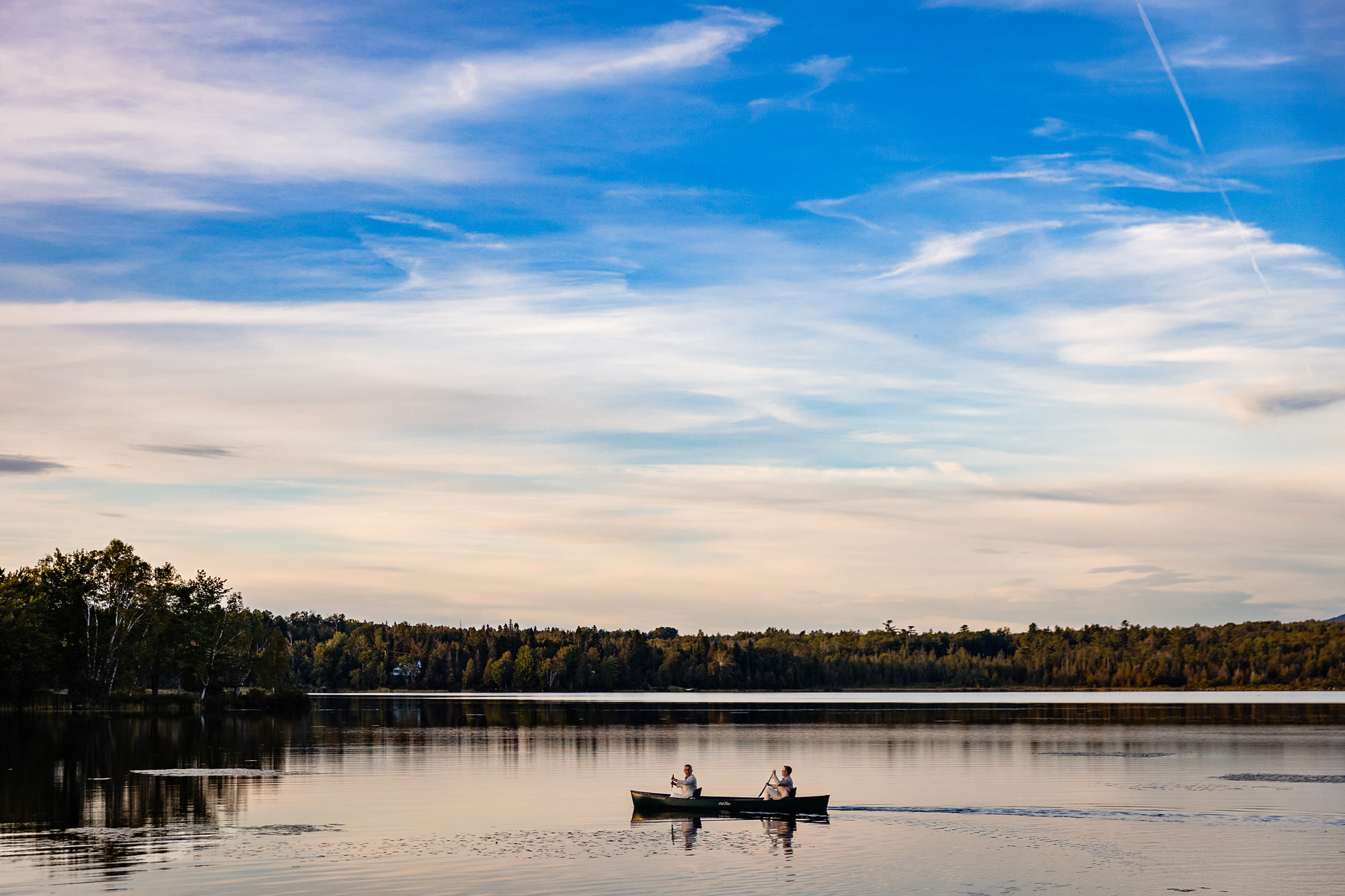 The grooms jumped into a canoe for sunset portraits at their wedding in Rangeley Maine