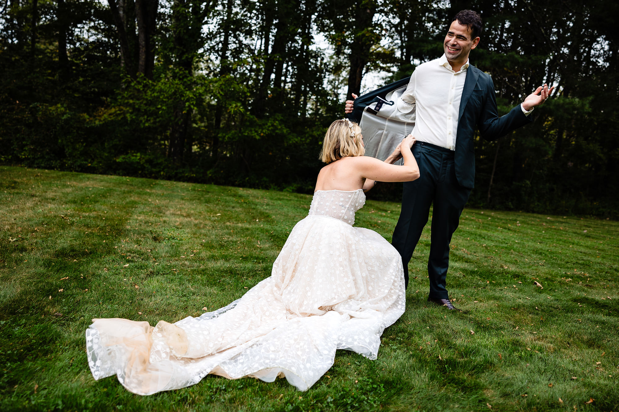 The bride fixes the groom's pants at their wedding in southern Maine.